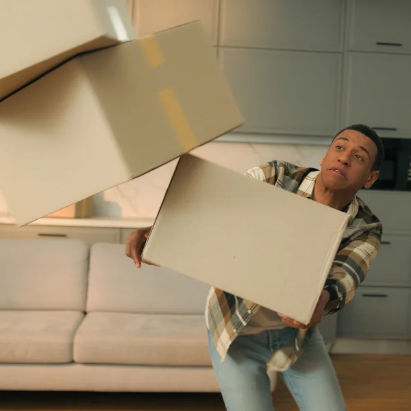 Un homme tient une boîte dans ses mains, illustrant les erreurs à éviter lors d’un déménagement.