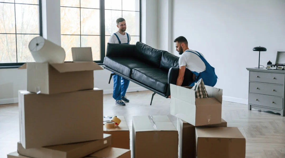 Deux hommes déplacent des meubles dans un appartement, illustrant des services de déménagement professionnels.